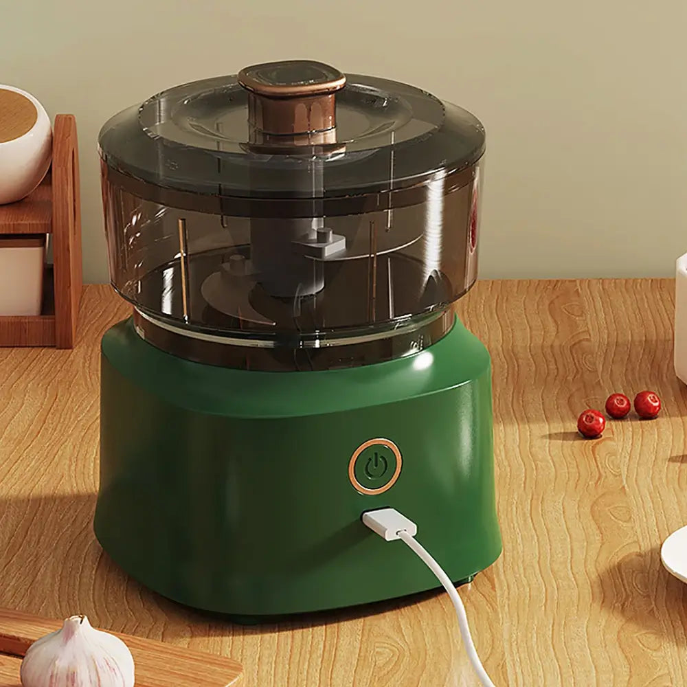 The mini electric meat grinder mincer machine in green, plugged in charging via its USB charging cable.