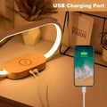 The wireless charger night light on a desk charging a phone via USB.